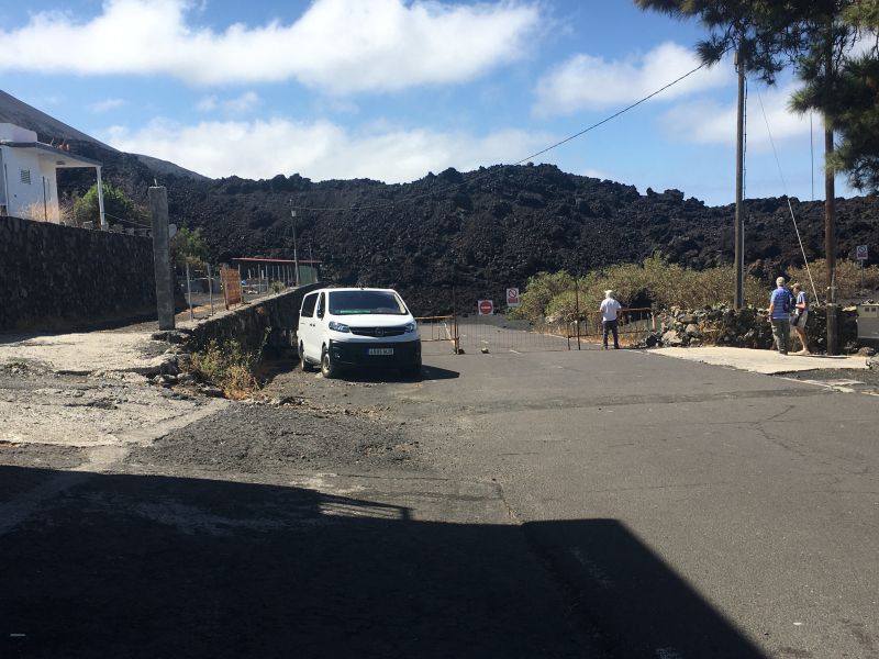 Lava flow next to a house
which also goes straight across a road.  
Link-words: LaPalma2024